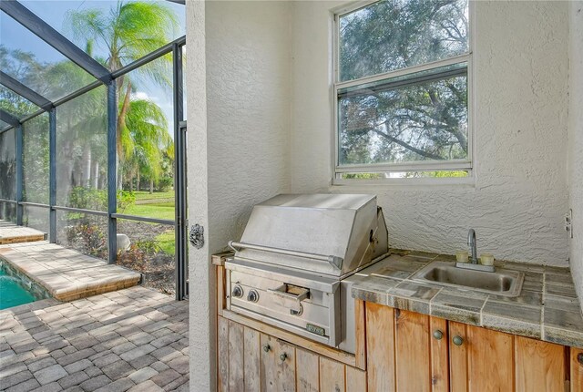 view of patio / terrace with a lanai, sink, a grill, and area for grilling