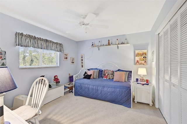 bedroom with ceiling fan, light carpet, and a closet