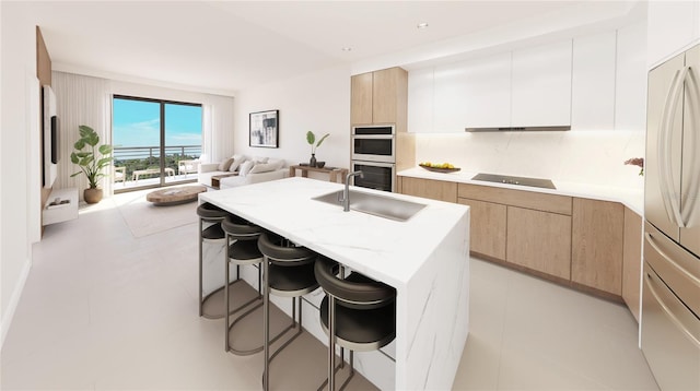 kitchen with a kitchen breakfast bar, stainless steel appliances, a kitchen island with sink, sink, and white cabinets