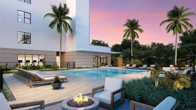 pool at dusk featuring a patio and a fire pit