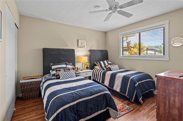 bedroom featuring dark hardwood / wood-style floors, ceiling fan, and a textured ceiling