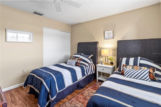 bedroom with a textured ceiling, ceiling fan, a closet, and dark hardwood / wood-style floors