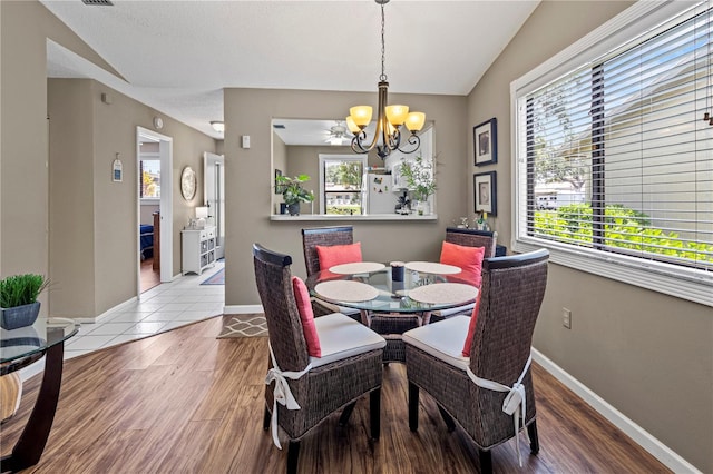 dining space with a chandelier, light hardwood / wood-style flooring, and lofted ceiling