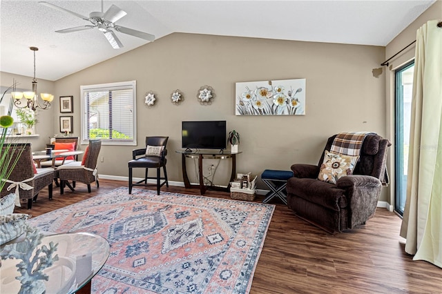 living room with ceiling fan with notable chandelier, dark hardwood / wood-style floors, vaulted ceiling, and plenty of natural light