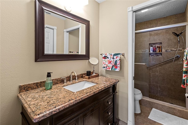 bathroom featuring a textured ceiling, vanity, tiled shower, tile patterned flooring, and toilet