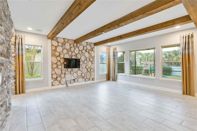 unfurnished living room featuring beamed ceiling, a healthy amount of sunlight, and a stone fireplace