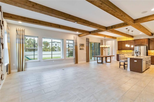 kitchen with a kitchen island with sink, a kitchen breakfast bar, stainless steel fridge with ice dispenser, pendant lighting, and decorative backsplash