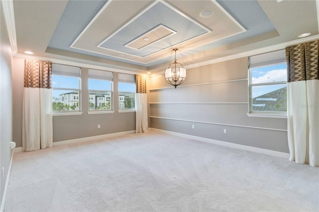 empty room featuring a raised ceiling, carpet, and an inviting chandelier