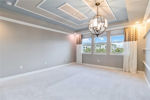 carpeted empty room featuring a notable chandelier, a raised ceiling, and ornamental molding