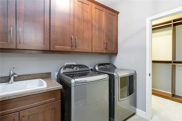 clothes washing area with cabinets, separate washer and dryer, light hardwood / wood-style floors, and sink