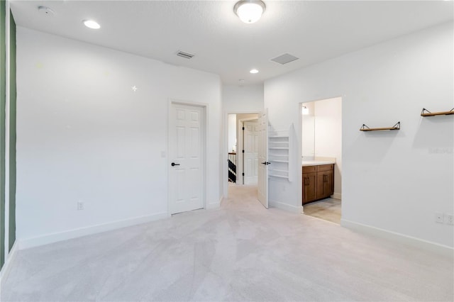 unfurnished bedroom featuring light carpet and ensuite bath