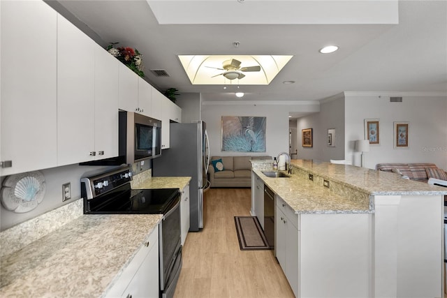 kitchen with appliances with stainless steel finishes, a skylight, ornamental molding, light hardwood / wood-style flooring, and white cabinetry