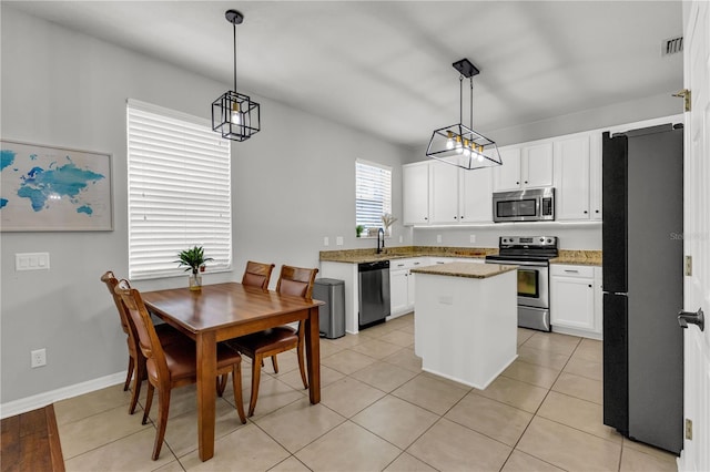 kitchen featuring decorative light fixtures, a kitchen island, white cabinetry, and appliances with stainless steel finishes