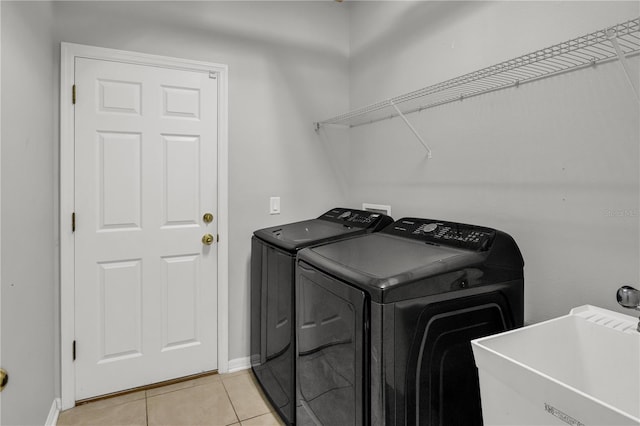 laundry area featuring light tile patterned floors, separate washer and dryer, and sink