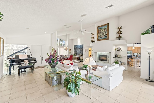 tiled living room with a textured ceiling, high vaulted ceiling, ceiling fan, and a premium fireplace