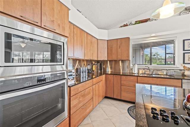 kitchen with sink, stainless steel appliances, a textured ceiling, lofted ceiling, and light tile patterned floors