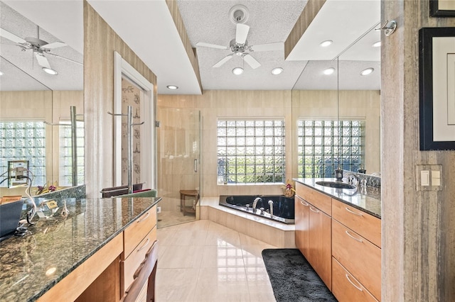 bathroom featuring vanity, ceiling fan, plus walk in shower, and a textured ceiling