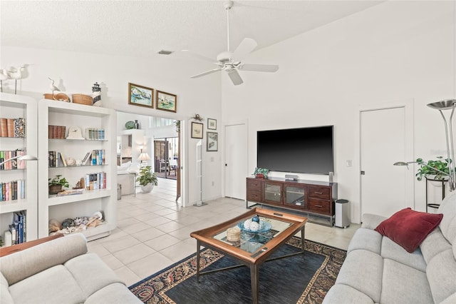 tiled living room featuring ceiling fan, a textured ceiling, high vaulted ceiling, and built in shelves