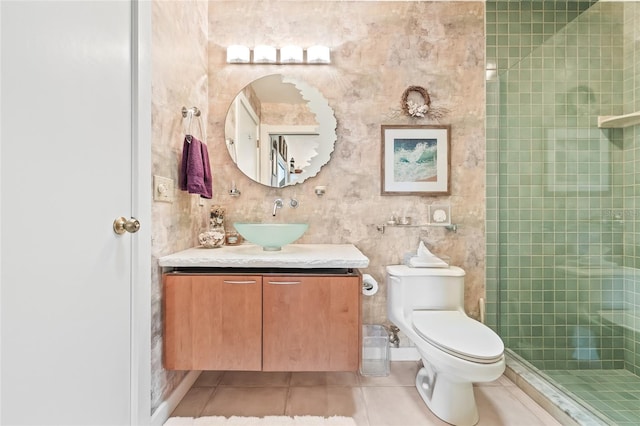 bathroom with tile patterned flooring, toilet, a tile shower, and vanity