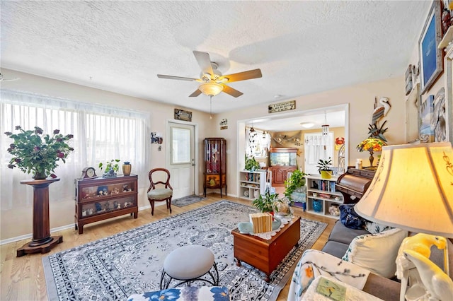 living room featuring a textured ceiling, light hardwood / wood-style flooring, and ceiling fan