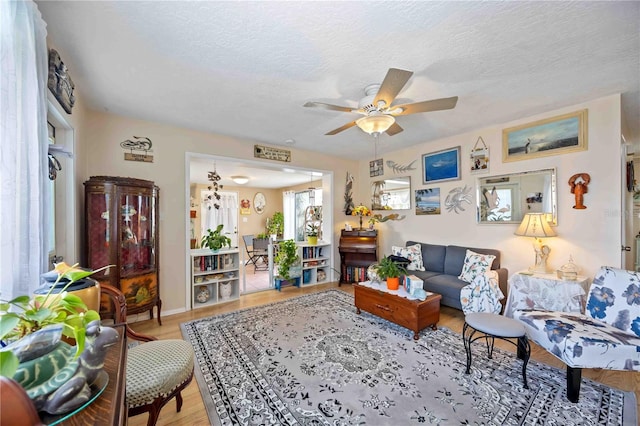 living room with ceiling fan, light hardwood / wood-style floors, and a textured ceiling