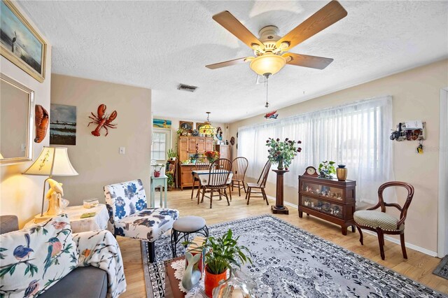 2057 Garden Pkwy, Bradenton, FL 34205 - living area featuring a textured ceiling, light wood-type flooring, ceiling fan, and baseboards