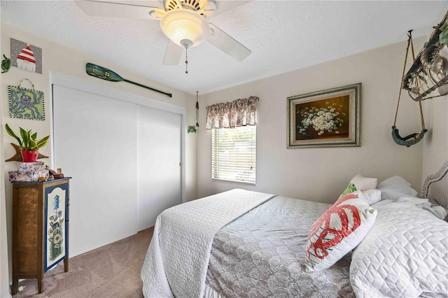 bedroom featuring ceiling fan, light colored carpet, and a textured ceiling