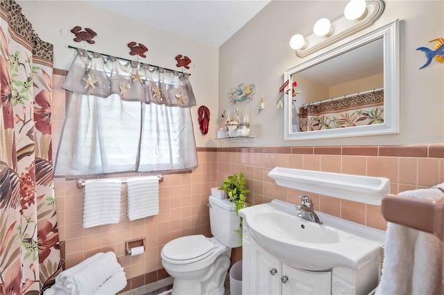 bathroom featuring vanity, tile walls, and toilet