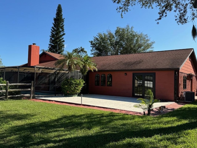 rear view of property featuring glass enclosure, cooling unit, a patio area, and a yard