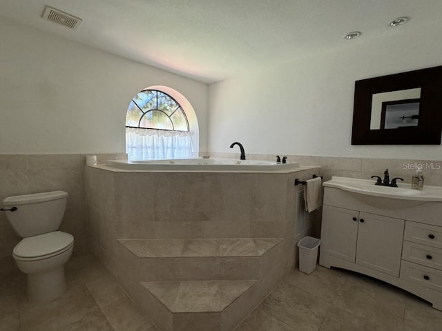 bathroom with tile patterned floors, vanity, tile walls, and toilet