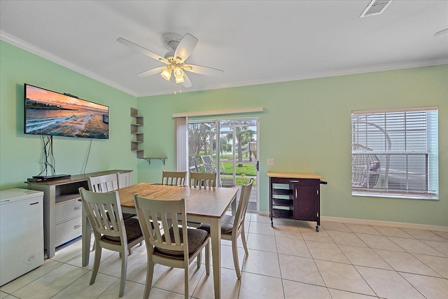 tiled dining space with ceiling fan and ornamental molding