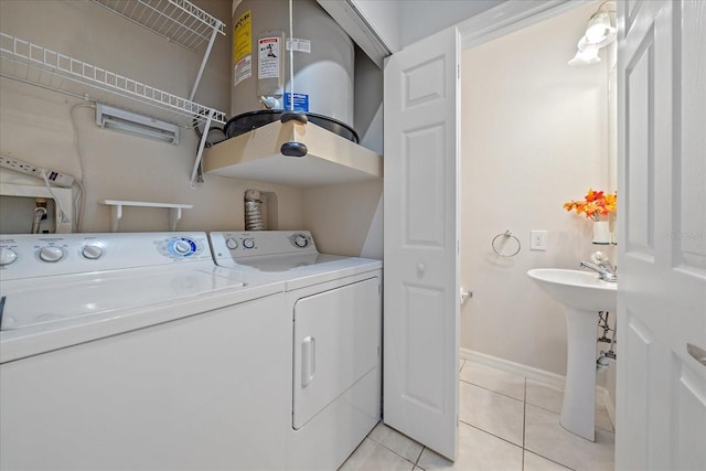 laundry room featuring light tile patterned floors, sink, washer and clothes dryer, and water heater