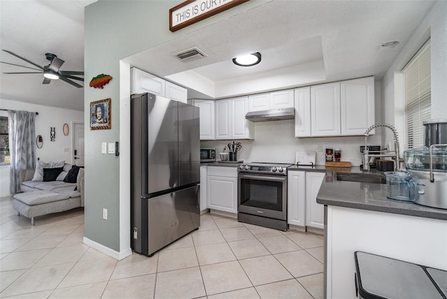 kitchen with white cabinetry, sink, a tray ceiling, light tile patterned flooring, and appliances with stainless steel finishes