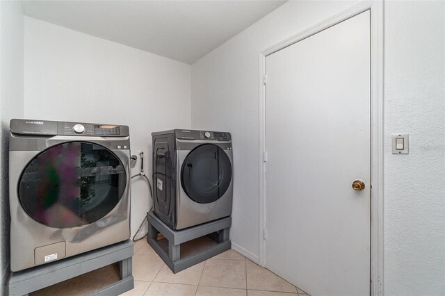 clothes washing area with washing machine and dryer and light tile patterned floors