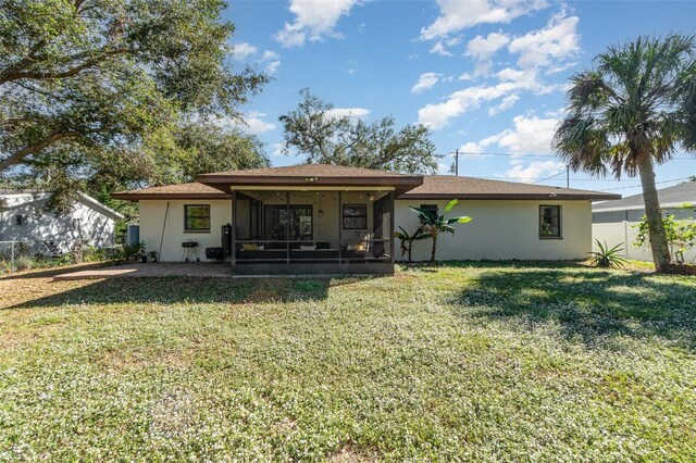 rear view of property with a yard, a patio area, and a sunroom