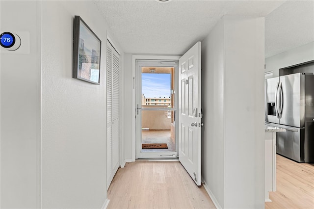 hallway with light hardwood / wood-style floors and a textured ceiling