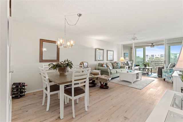 dining space featuring a textured ceiling, ceiling fan with notable chandelier, and light hardwood / wood-style flooring