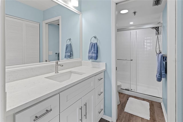 bathroom with toilet, an enclosed shower, wood-type flooring, and vanity