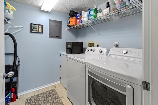 laundry area with separate washer and dryer, electric panel, a textured ceiling, and light wood-type flooring