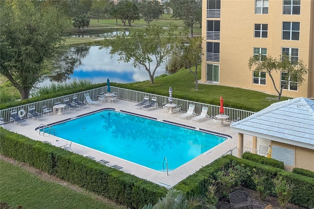 view of pool with a lawn and a water view