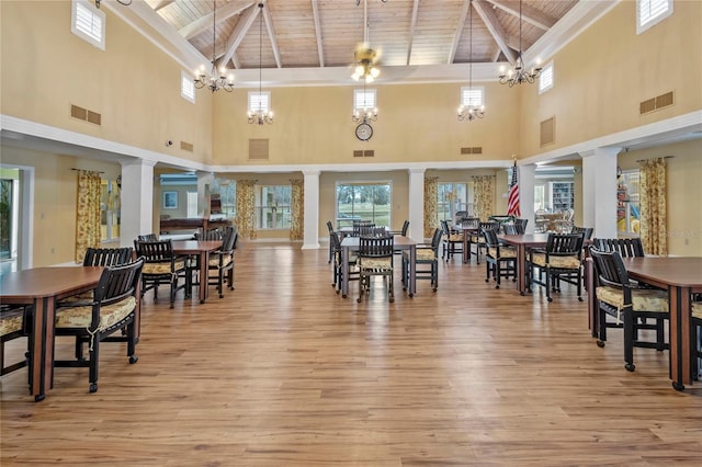 dining area featuring light hardwood / wood-style floors, high vaulted ceiling, decorative columns, and wooden ceiling