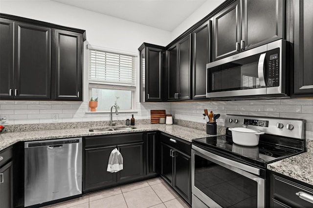 kitchen with decorative backsplash, appliances with stainless steel finishes, light stone countertops, sink, and light tile patterned floors