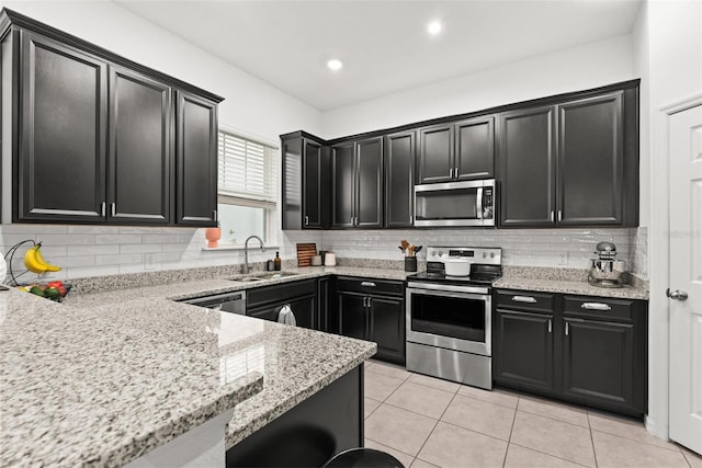 kitchen featuring light stone countertops, tasteful backsplash, stainless steel appliances, sink, and light tile patterned floors