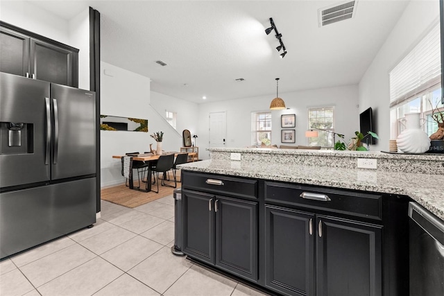 kitchen with light tile patterned flooring, pendant lighting, dishwasher, stainless steel refrigerator with ice dispenser, and light stone countertops