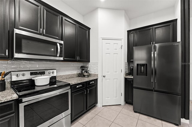 kitchen with light stone counters, stainless steel appliances, light tile patterned flooring, and decorative backsplash