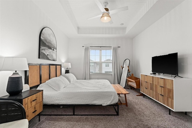 carpeted bedroom with ceiling fan and a tray ceiling