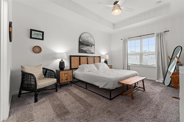 carpeted bedroom featuring a raised ceiling and ceiling fan