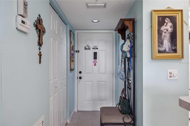 doorway to outside with light tile patterned floors and a textured ceiling