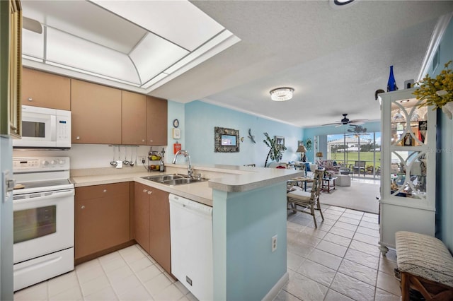 kitchen featuring ceiling fan, sink, kitchen peninsula, a textured ceiling, and white appliances