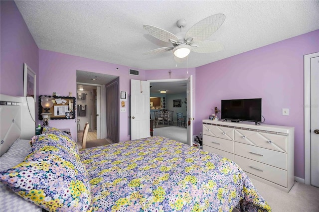 bedroom with a textured ceiling, ceiling fan, and light carpet